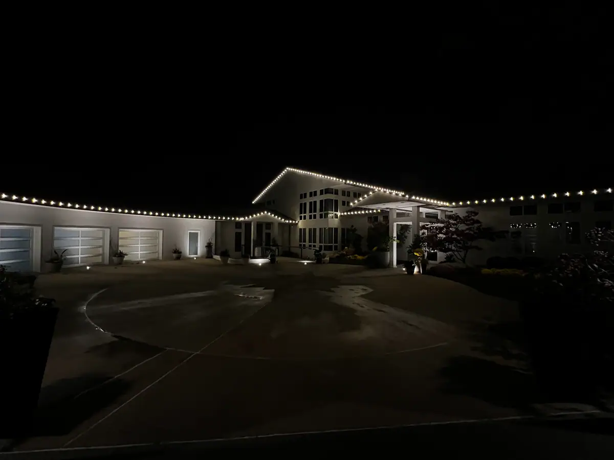 A long low home lit end to end in warm white along a circular drive