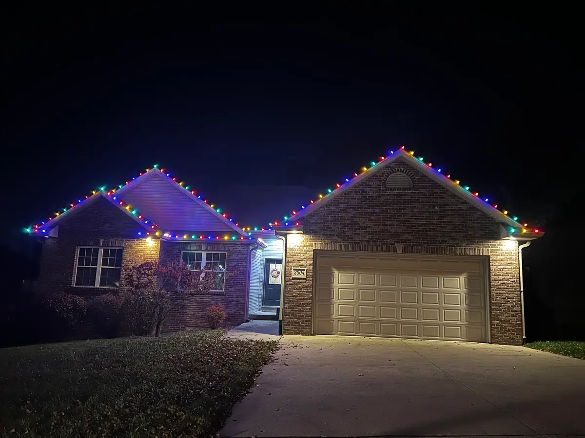 A brick ranch home with vivid multicolor C9 lights across the rooflines